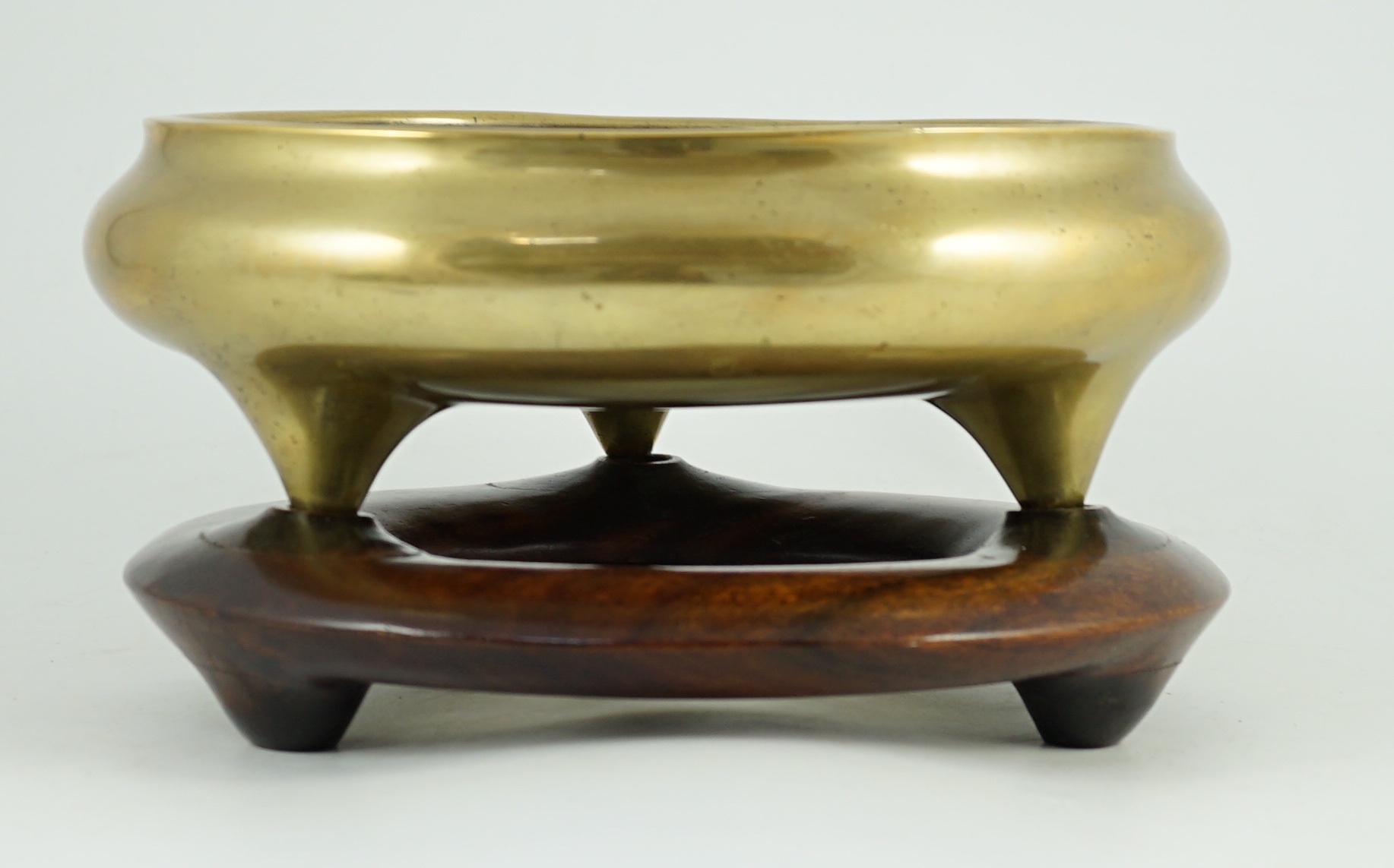 A large Chinese polished bronze tripod censer, 19th century, private four character seal mark, 29.5 cm diameter, Disc shaped rosewood stand